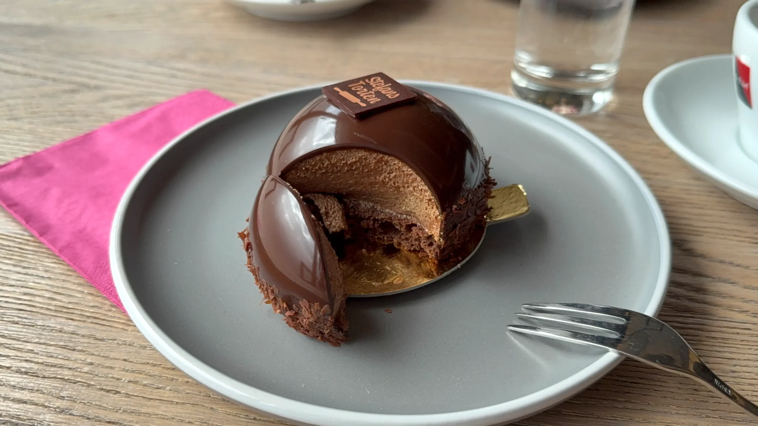 Kaffee und feine Törtchen von Stefans Torten auf Tellern mit pinker Serviette.