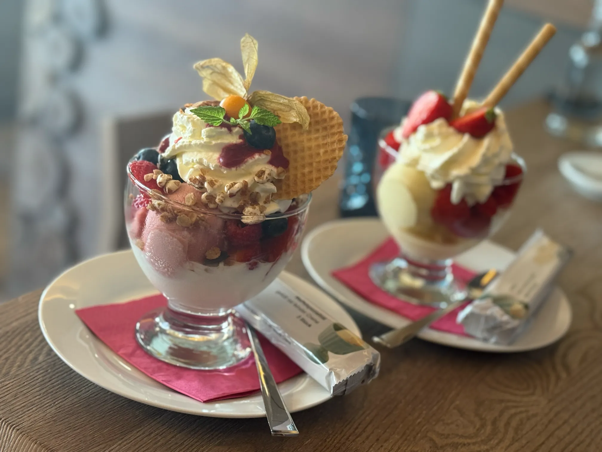 Zwei fruchtige Eisgläser mit Beeren und Sahne dekoriert